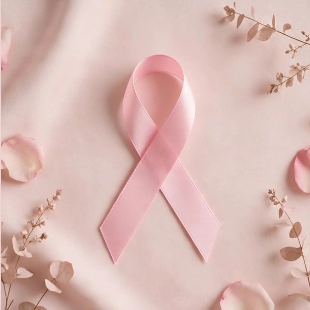 A pink breast cancer awareness ribbon on a soft pink background with petals